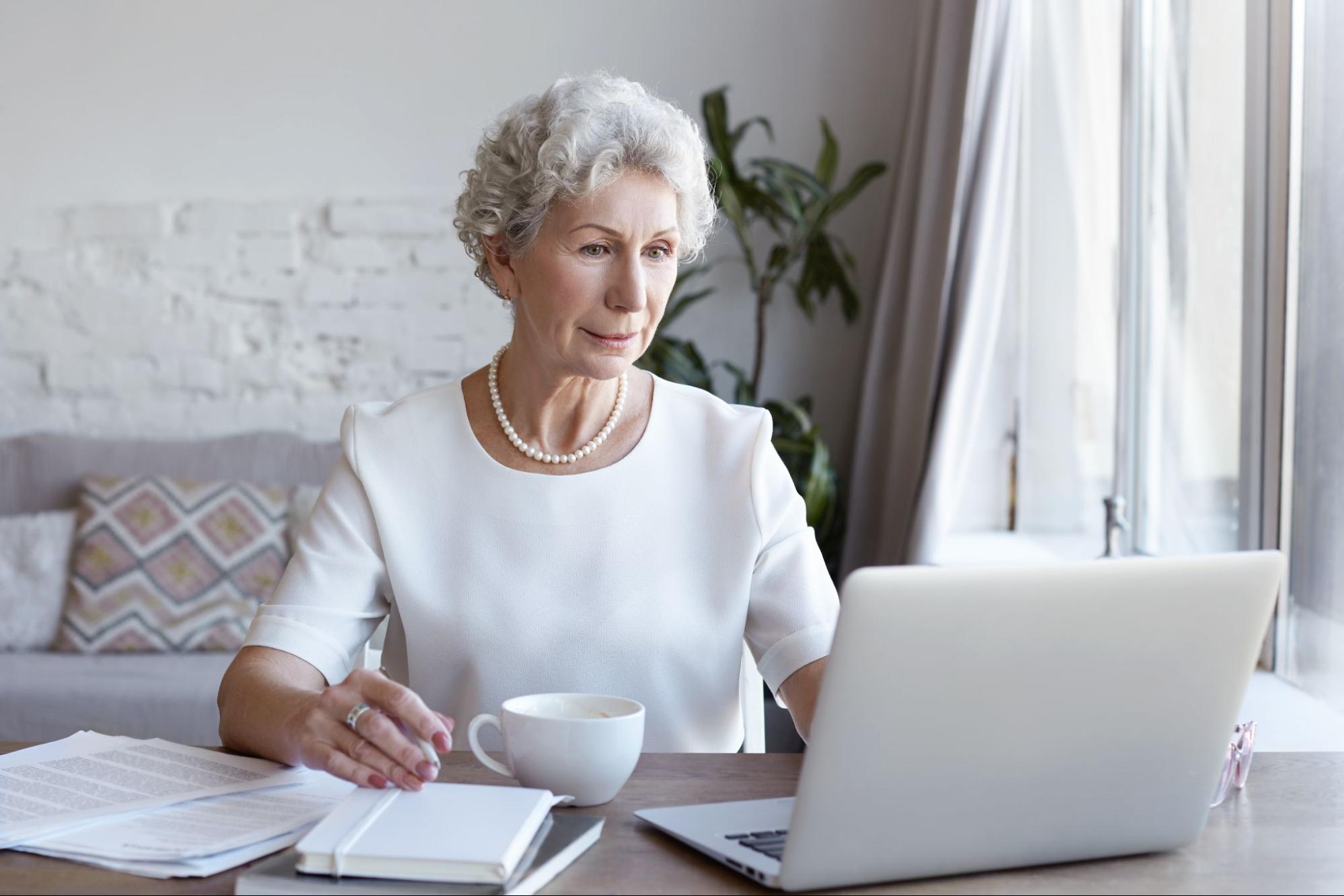 Безработная женщина пенсионер сидит за компьютером и