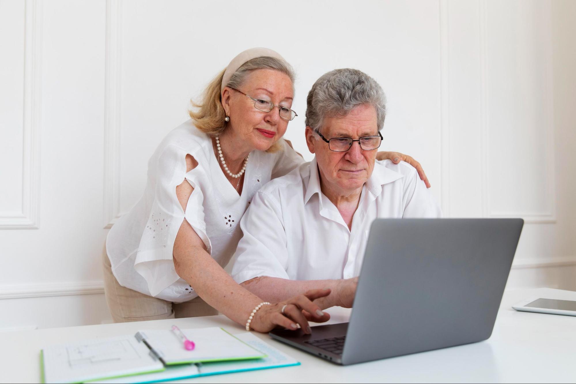 Пожилая пара пенсионеров смотрят информацию о пенсионных льготах за компьютером